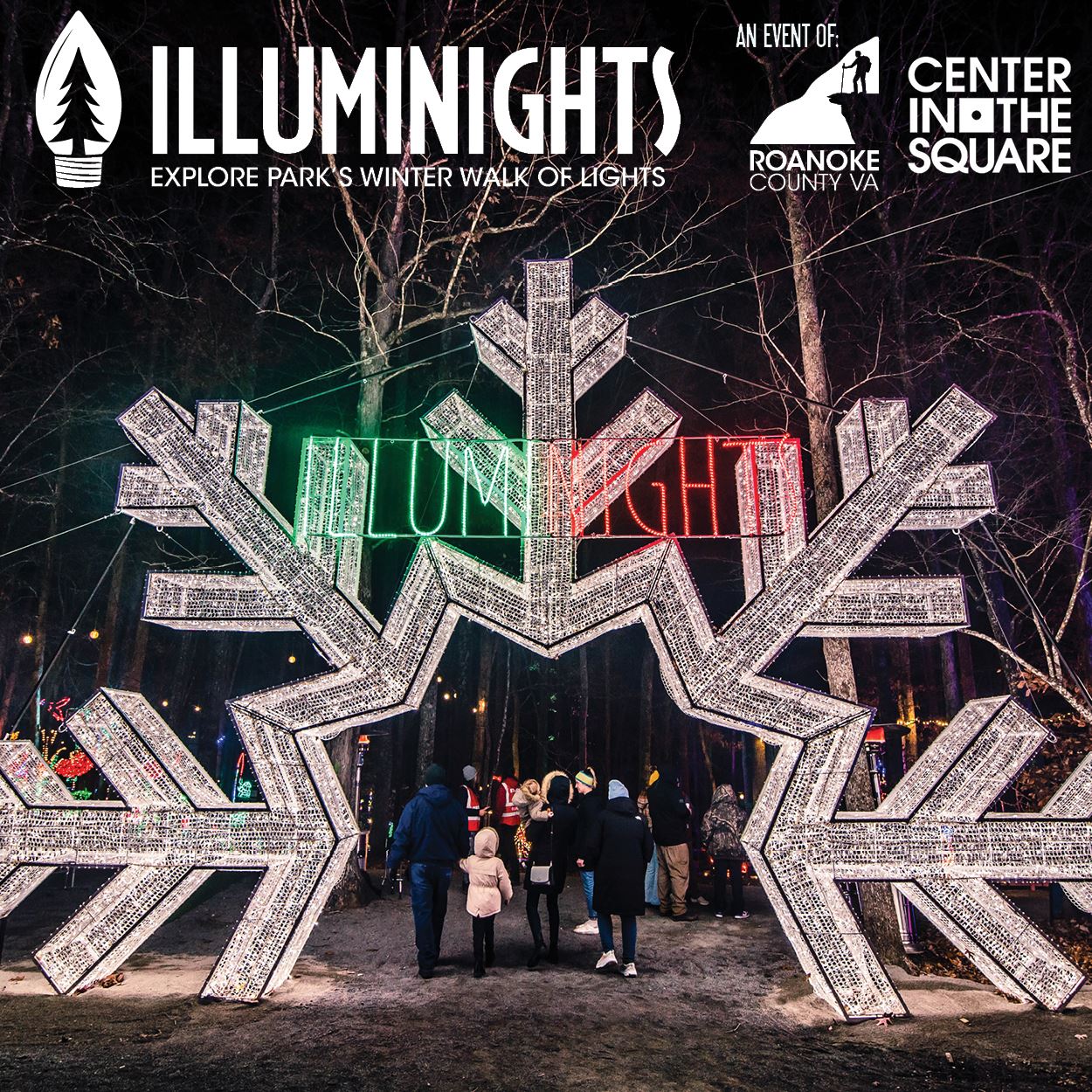 People walk through a giants light-up snowflake